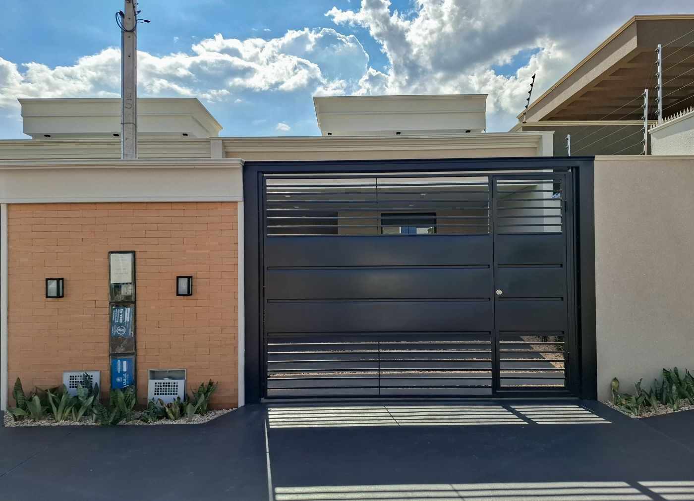 Portão da garagem e parede de tijolinho com arandelas