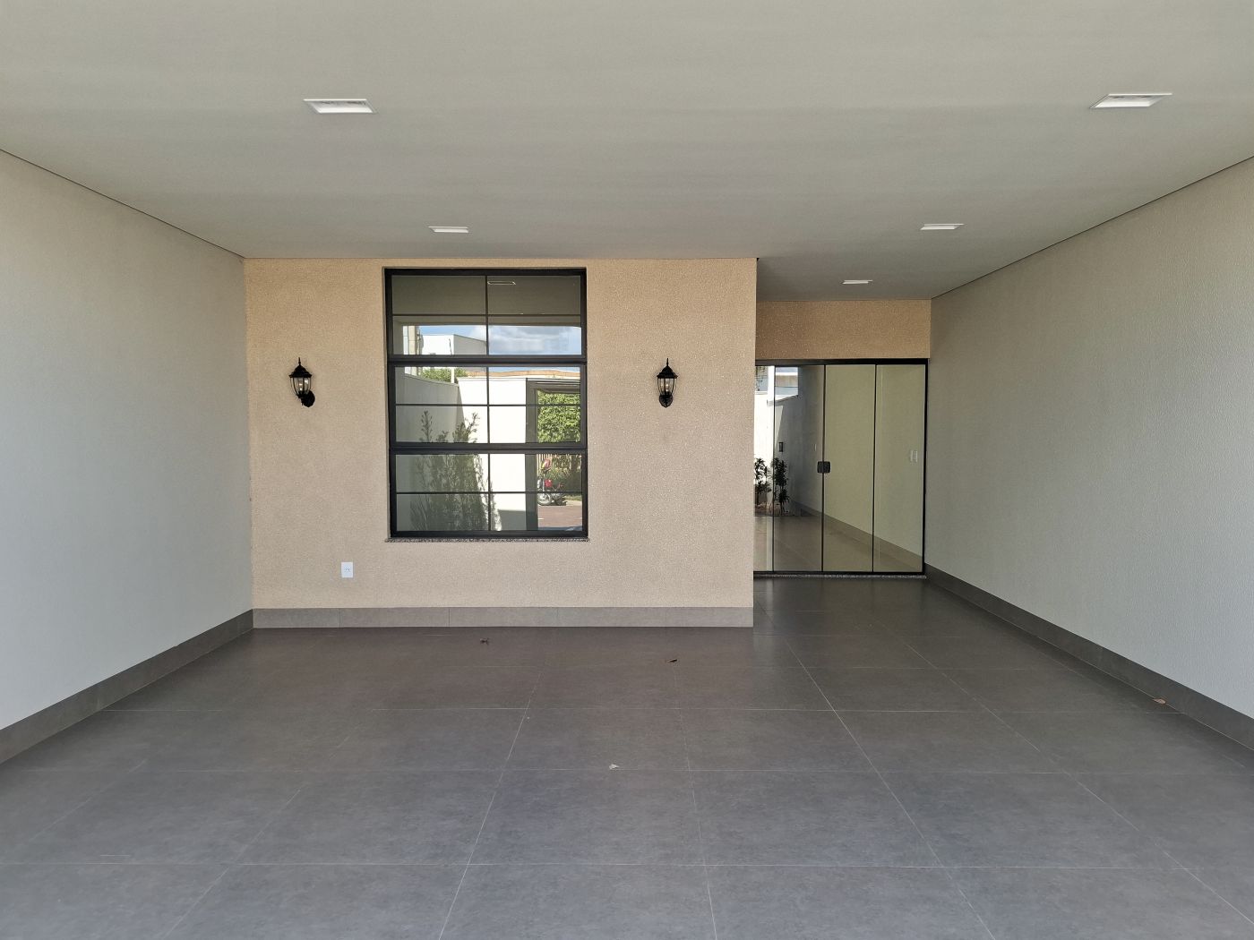 Fachada da sala vista da garagem, com janela de quadros pretos e arandelas