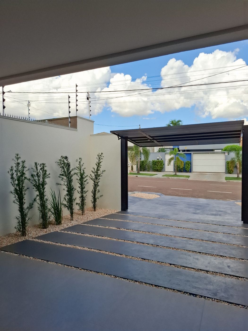 Garagem vista para a rua, com pergolado e jardim