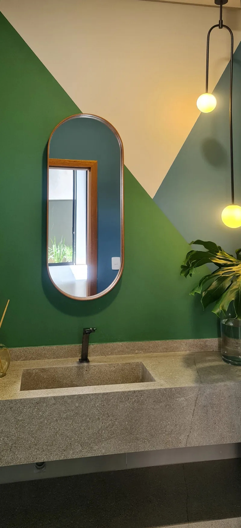 Lavabo com parede verde, espelho oval e bancada de pedra
