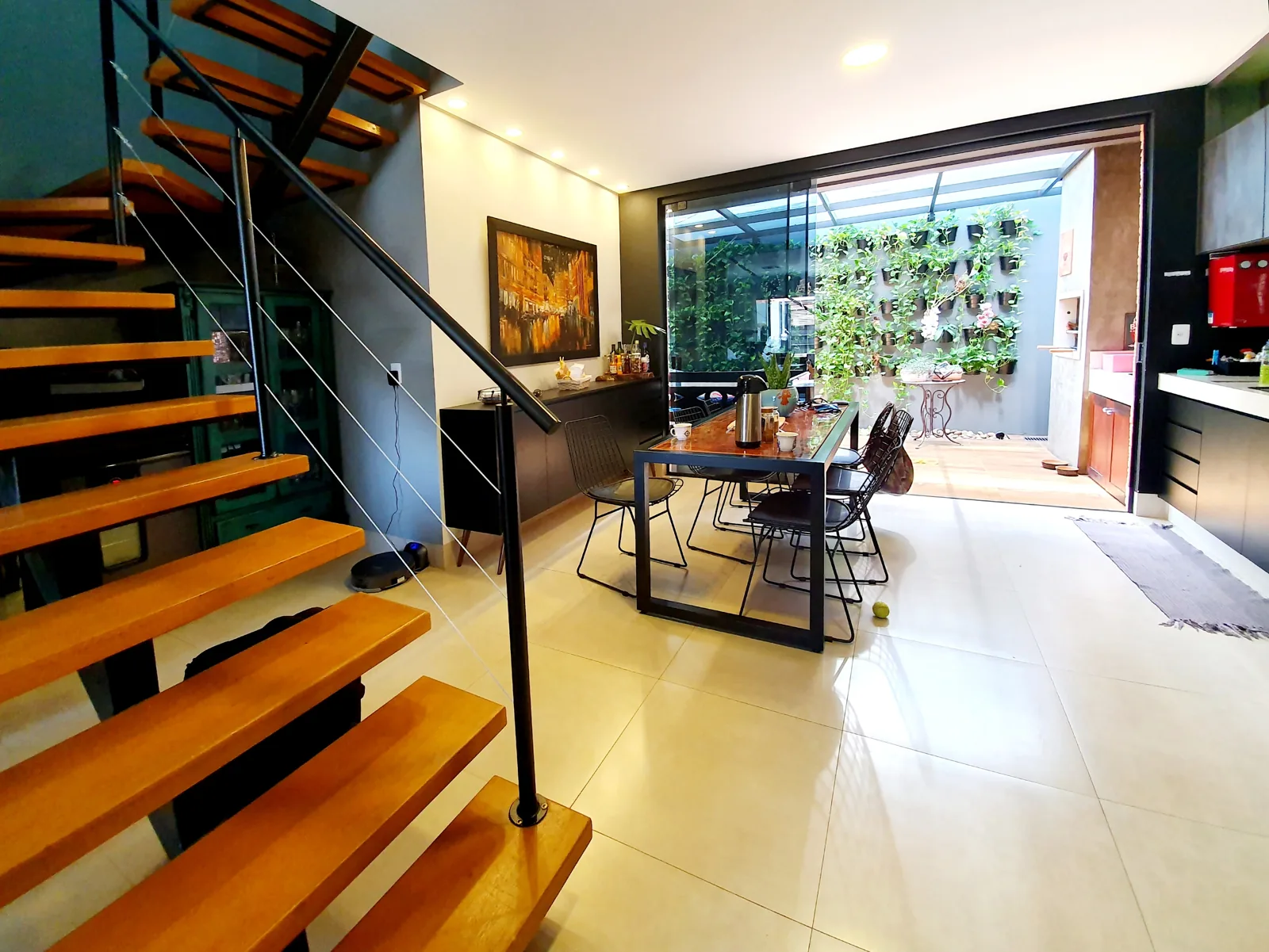 Sala integrada com escada de madeira e jardim vertical ao fundo